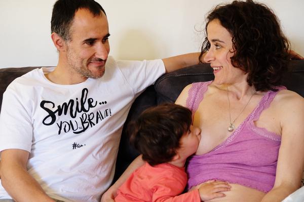 Noelia y su pareja, sentados en el sofá, se miran cómplices sonriendo mientras Aimar mama.