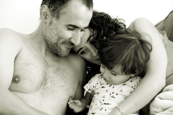 Blanco y negro. Sergio (el papá) con el torso desnudo mira cómo Aimar toca su pezón, curioso. Mientras, Noelia observa la escena con la cabeza apollada en el hombro de Sergio